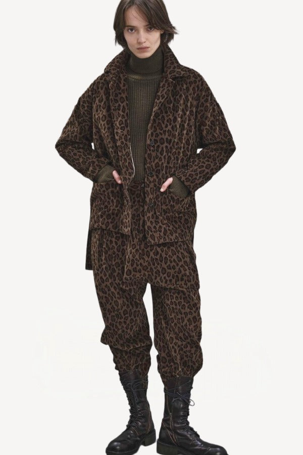 Front view of leopard yayla25 pants on model wearing green sweater, leopard jacket and boots, against a white background.