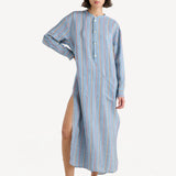 Front view of dusty blue tunic dress on model wearing small white wedge heels on white background.