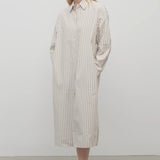 A blonde model standing at a front view in the midi dress with white background.