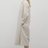 A blonde model standing at a side view in the midi dress with white background.