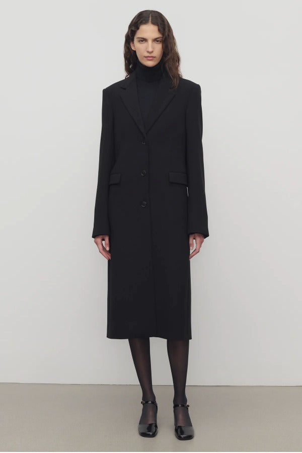 Front view of black cerys coat on model wearing black heels, against a white background.