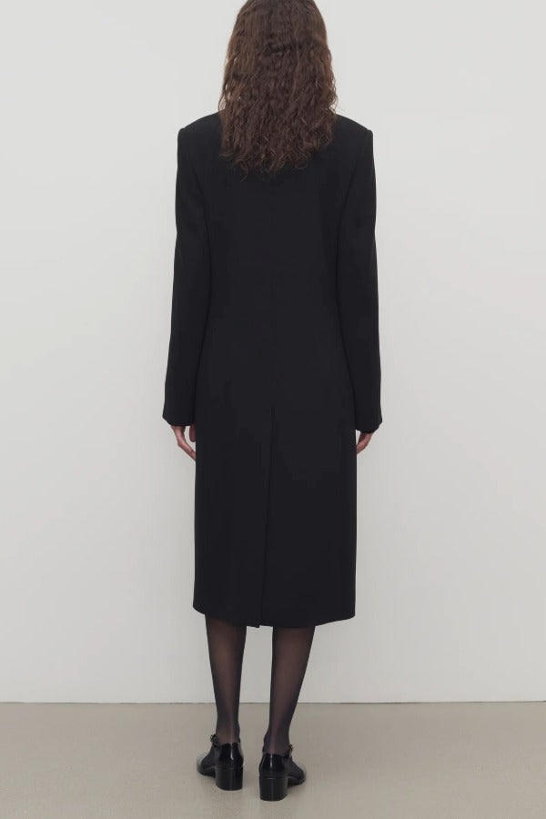Back view of black cerys coat on model wearing black heels, against a white background.
