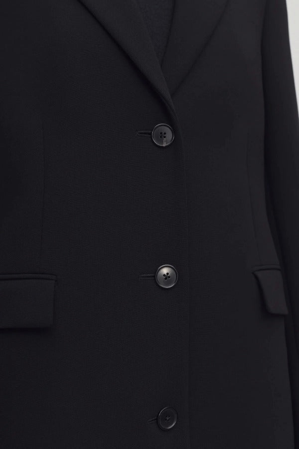 Middle closeup view of black cerys coat on model against a white background.