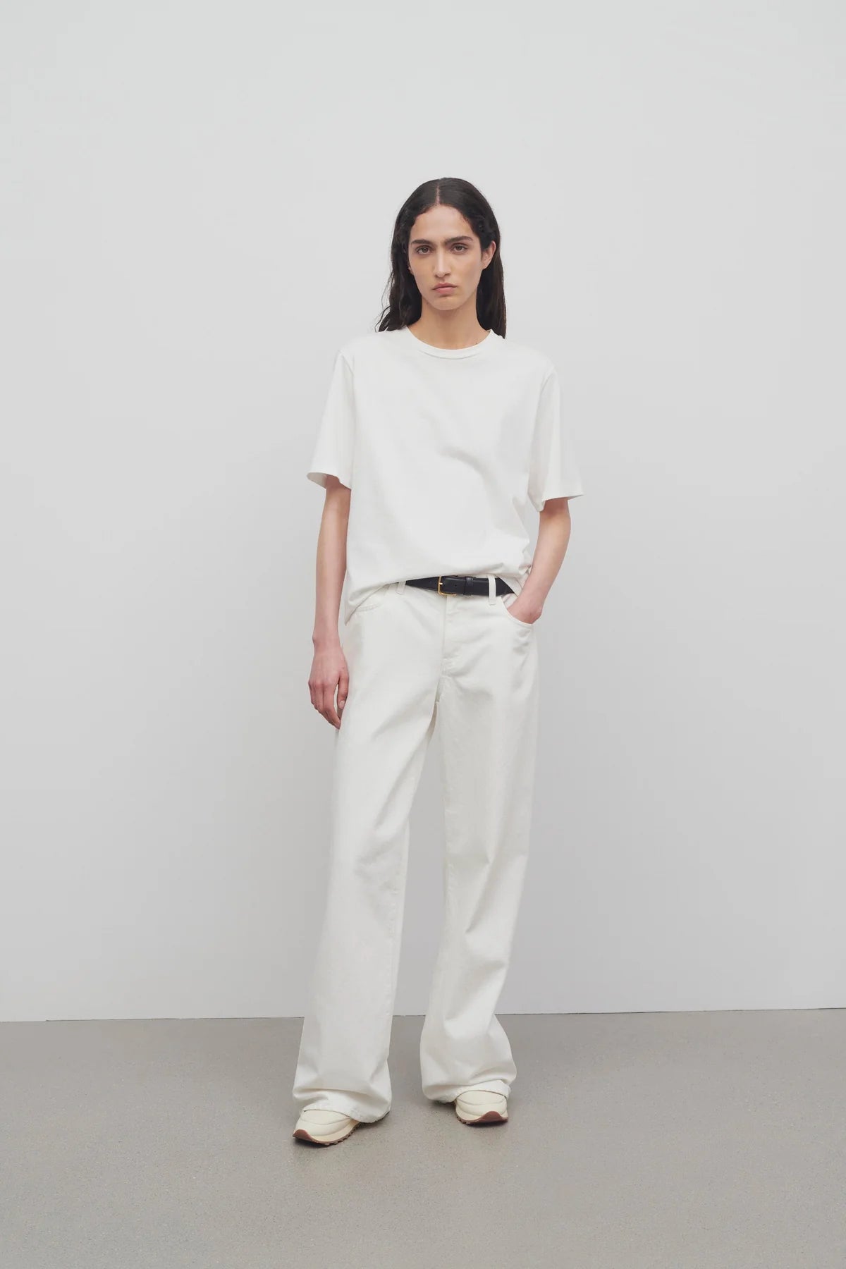 Front view of white eglitta jean on model wearing white t-shirt and sneakers, against a white background.