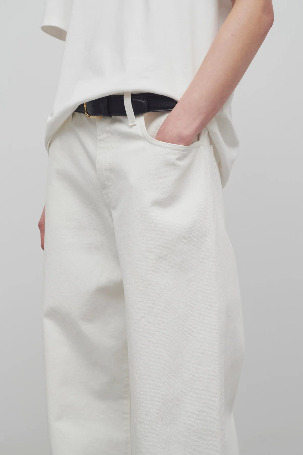 Front closeup view of white eglitta jean on model wearing white t-shirt, against a white background.