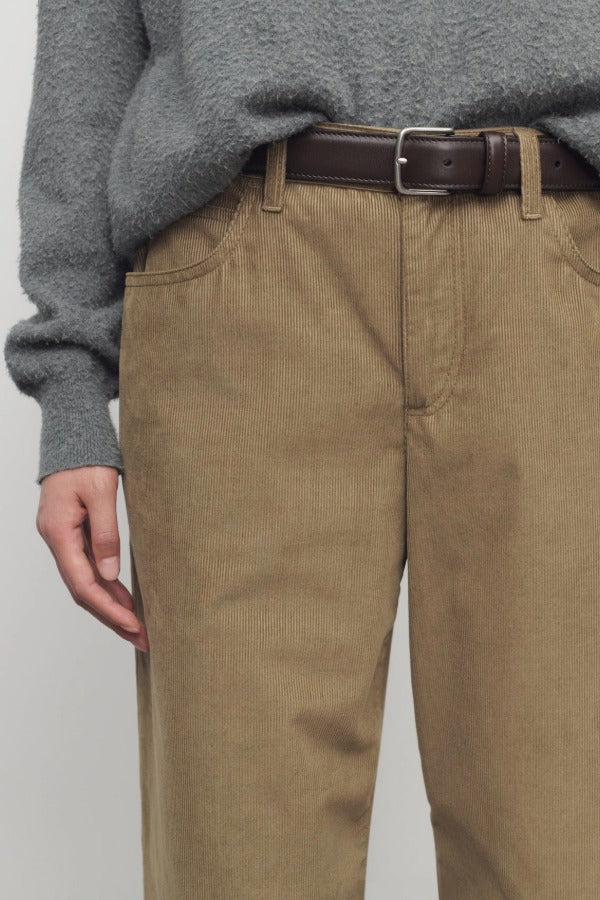 Front closeup of beige eglitta pant on model wearing grey sweater and brown belt, against a white background.