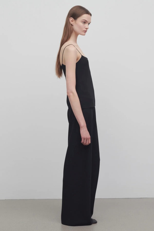 Side view of black gala pant on model wearing black top, against a white background.