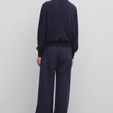 Back view of navy gala pant on model wearing black top, against a white background.
