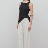 Front slanted view of off white gala pant on model wearing black tank top, against a white background.
