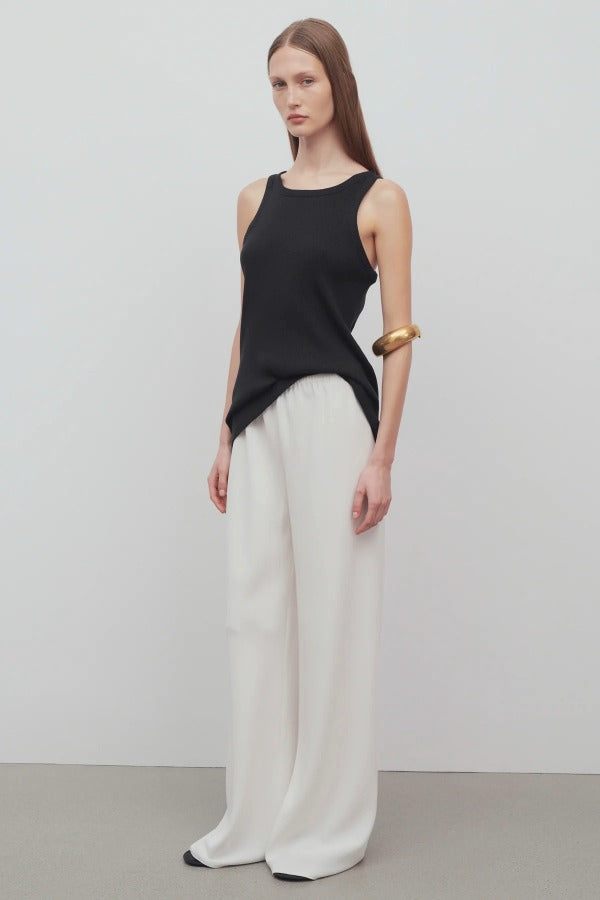 Front slanted view of off white gala pant on model wearing black tank top, against a white background.