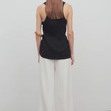 Back view of off white gala pant on model wearing black tank top, against a white background.