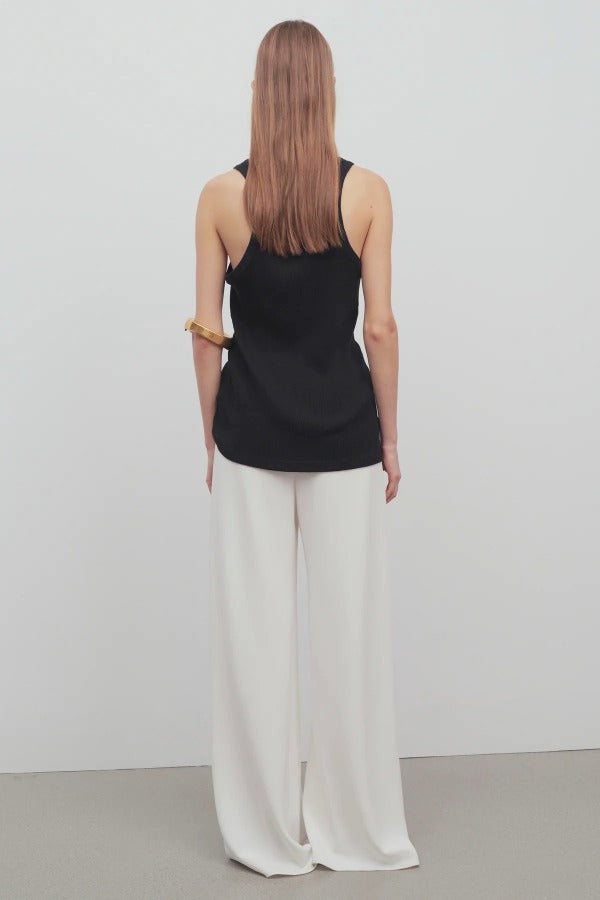 Back view of off white gala pant on model wearing black tank top, against a white background.