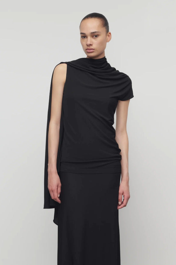 Front view of black isadra top on model wearing black skirt, against a white background.
