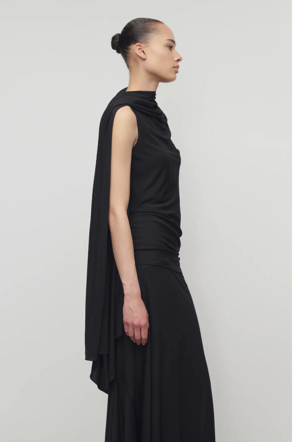 Side view of black isadra top on model wearing black skirt, against a white background.