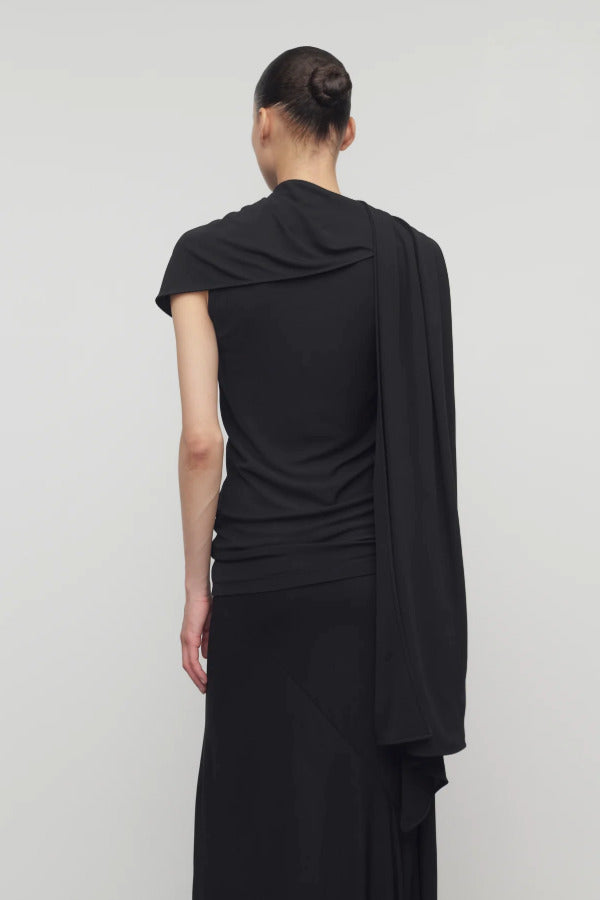 Back view of black isadra top on model wearing black skirt, against a white background.
