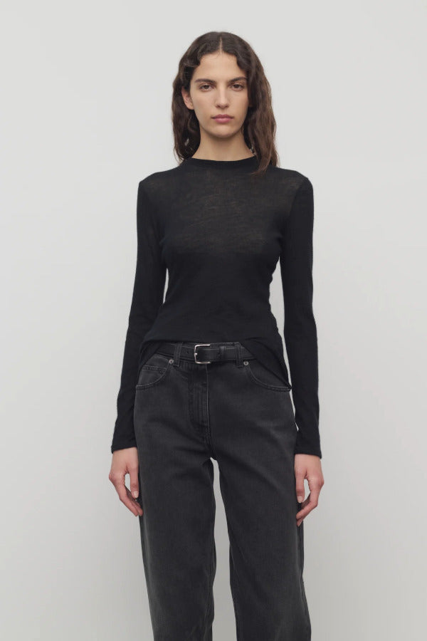 Front view of black iverness top on model wearing black jeans and belt against a white background.