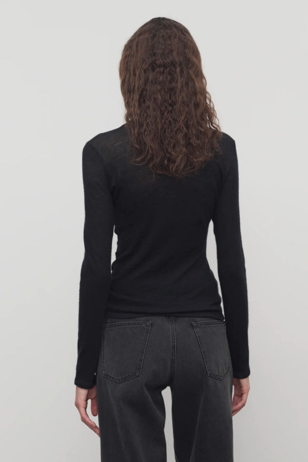 Back view of black iverness top on model wearing black jeans and belt, against a white background.