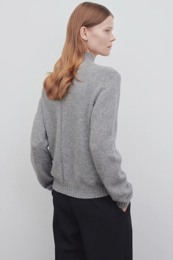 Back view of medium heather grey top on model wearing black trousers, against a white background.