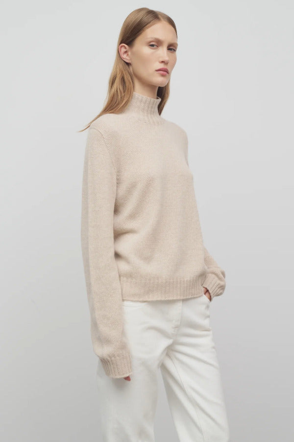 Front slanted view of oatmeal kensington top on model wearing white trousers, against a white background.