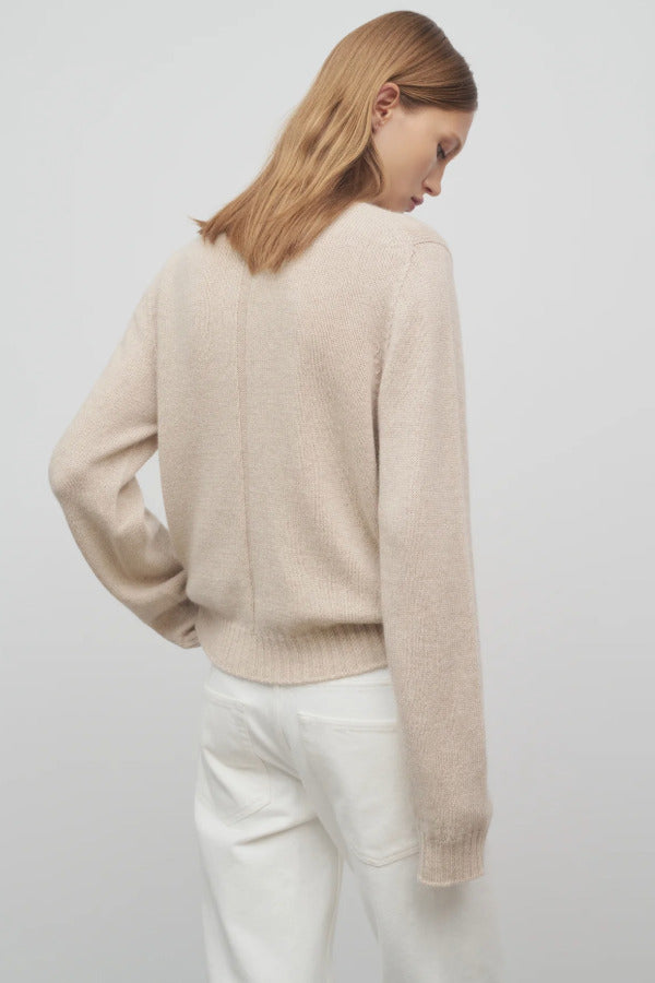 Back view of oatmeal kensington top on model wearing white trousers, against a white background.