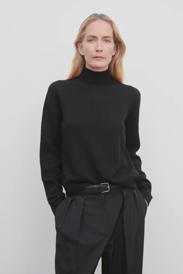 Front view of black kensington top on model wearing black trousers, against a white background.