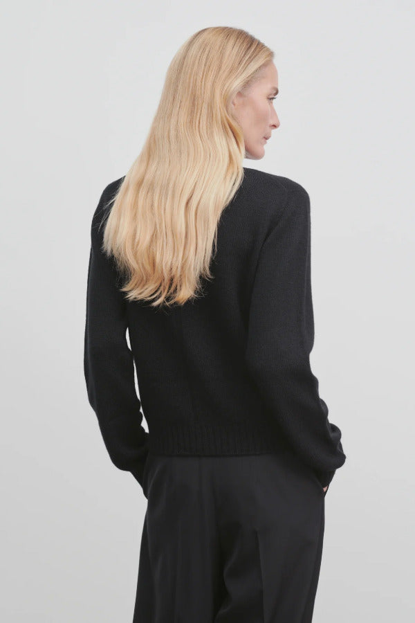 Back view of black kensington top on model wearing black trousers, against a white background.