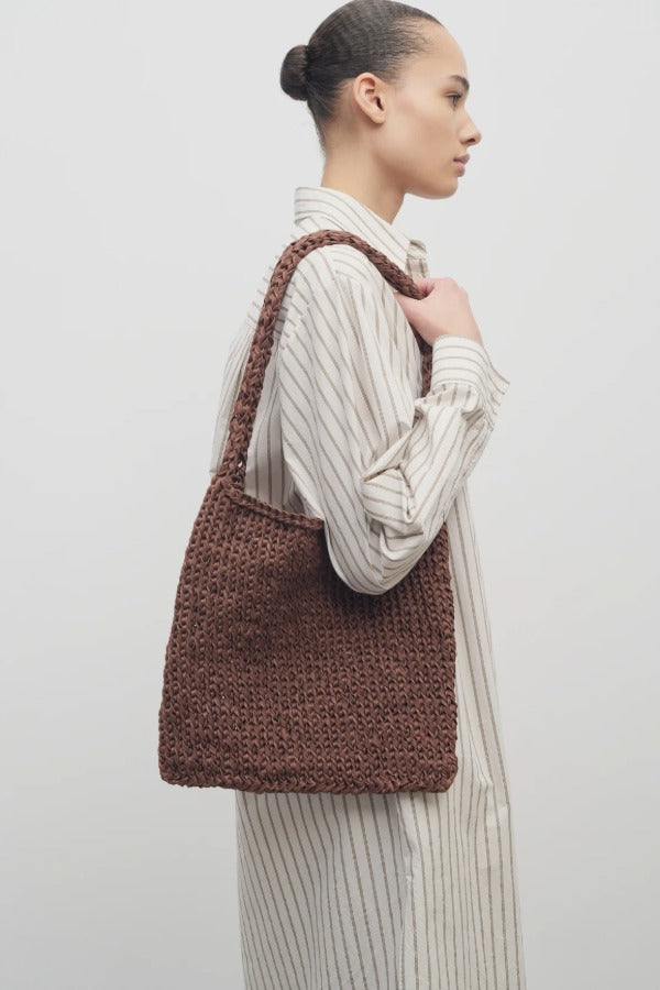 Front view of brown large didion bag on model wearing white striped dress, against a white background.