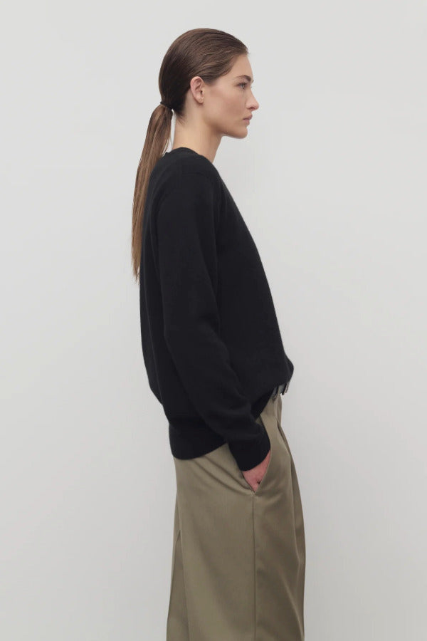 Side view of black leilani top on model wearing khaki pants, against a white background.