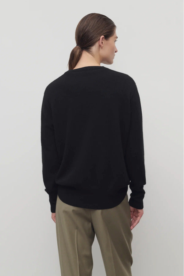 Back view of black leilani top on model wearing khaki pants, against a white background.
