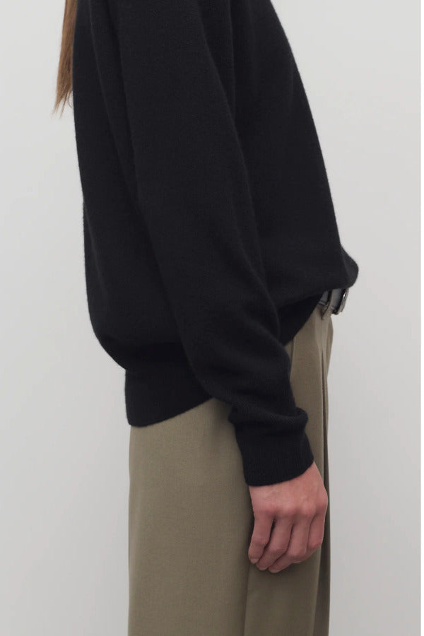 Side closeup view of black leilani top on model wearing khaki pants, against a white background.
