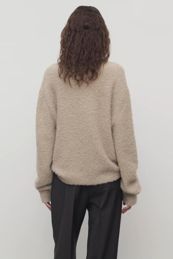 Back view of beige lethara sweater on model wearing black pants, against a white background.