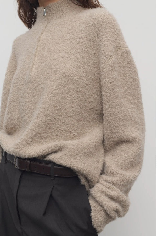 Front closeup view of beige lethara sweater on model wearing black pants, against a white background.