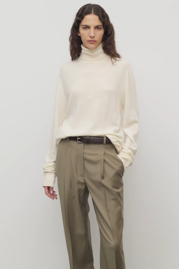 Front view of ivory lizzy top on model wearing khaki trousers and a brown belt, against a white background.
