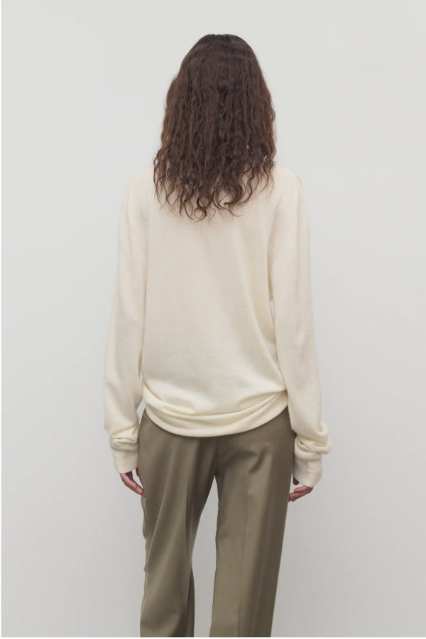 Back view of ivory lizzy top on model wearing khaki trousers, against a white background.