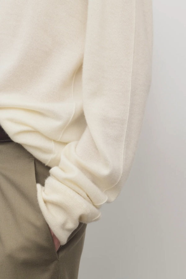 Side closeup view of ivory lizzy top on model wearing khaki trousers, against a white background.