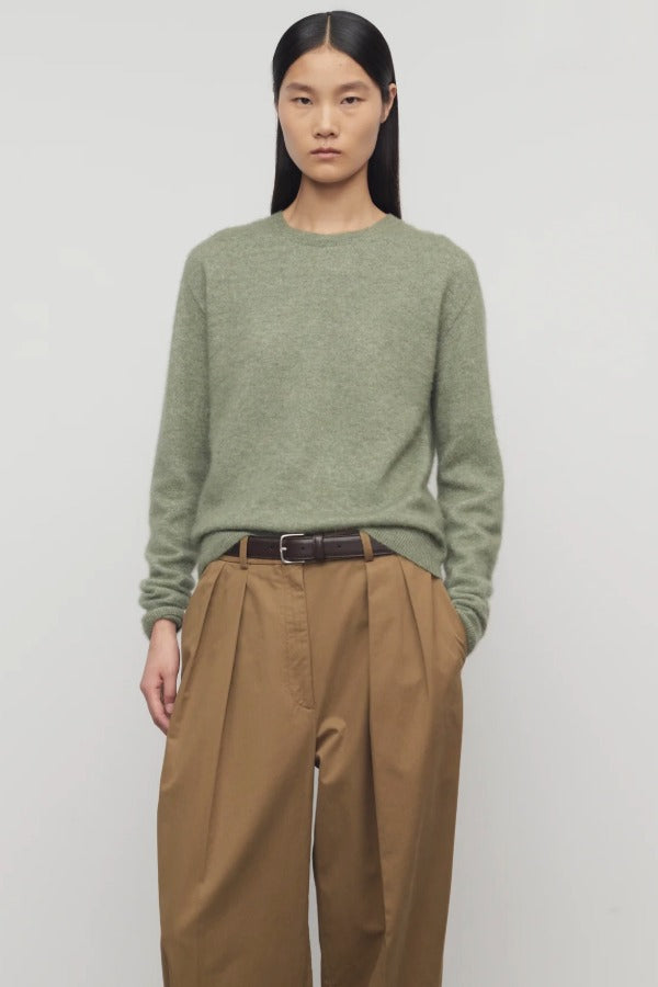 Front view of sage loynna top on model wearing camel trousers and brown belt, against a white background.