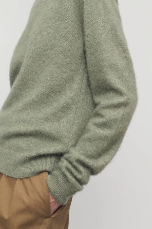 Side closeup view of sage lorynna top on model wearing camel trousers, against a white background.
