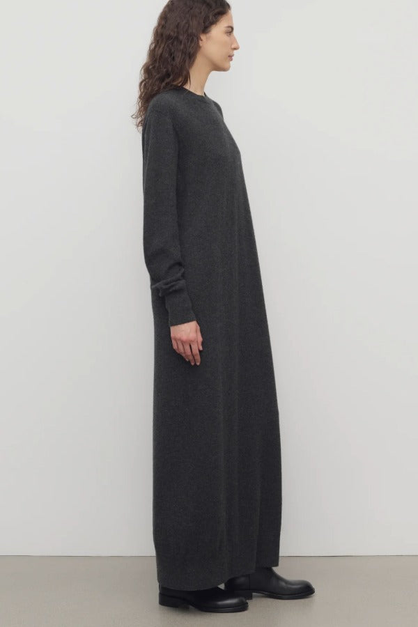 Side view of enzyme black loter dress on model wearing boots, against a white background.