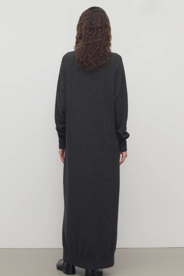 Back view of enzyme black loter dress on model wearing boots, against a white background.