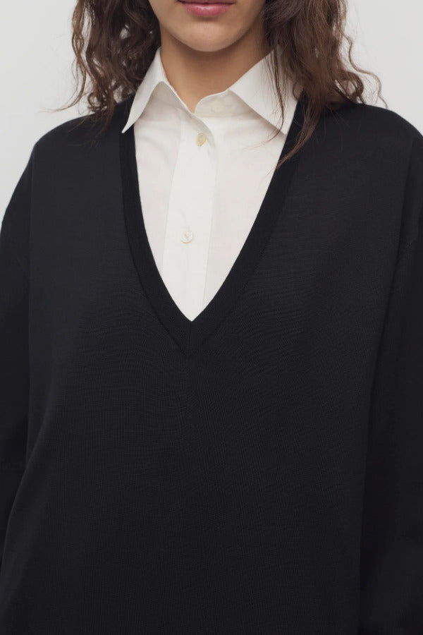 Front closeup view of black luza dress on model wearing white collar shirt, against a white background.