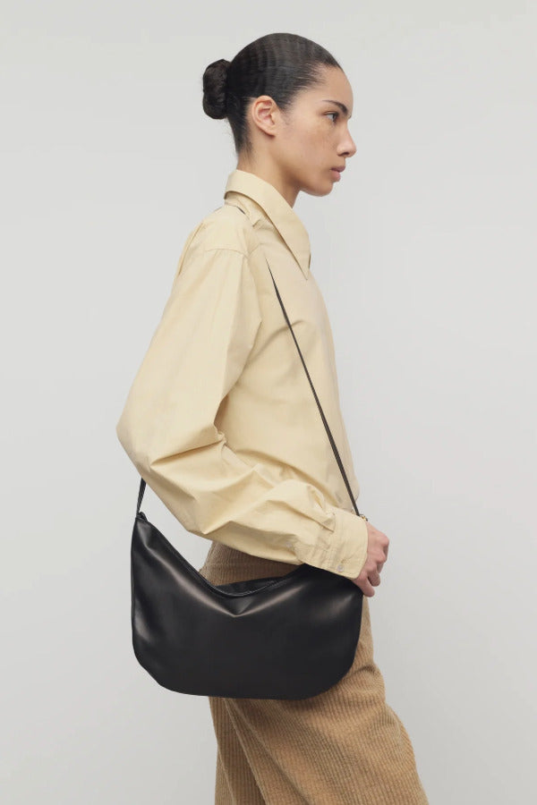 Side view of sand margan shirt on model wearing orange corduroys and brown shoulder bag, against a white background.