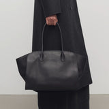 Front view of black marlo 14 bag on model wearing long black coat and boots, against a white background.