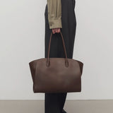 Front view of deep brown marlo 14 bag o model wearing grey pants, green shirt and mules against a white background.