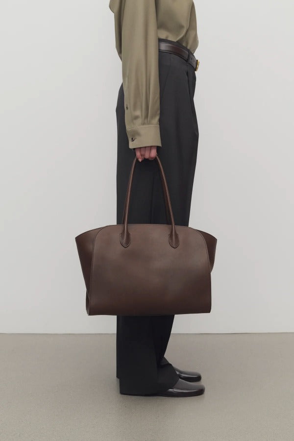 Front view of deep brown marlo 14 bag o model wearing grey pants, green shirt and mules against a white background.