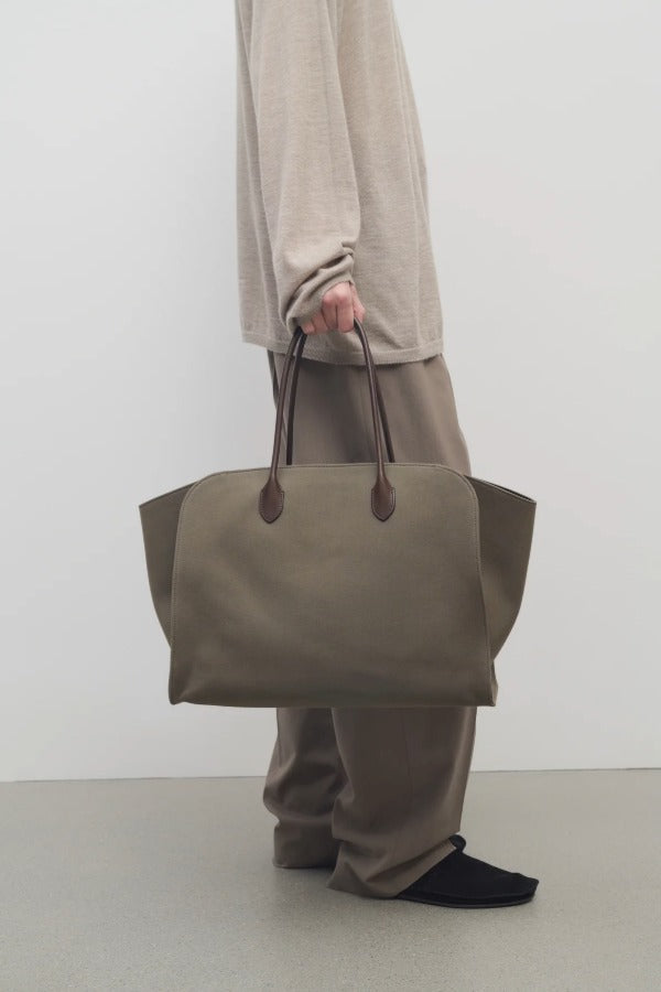 Front view of taupe marlo 17 bag on model wearing khaki pants and beige shirt, against a white background.