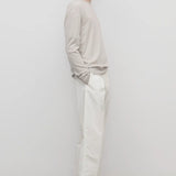 Side view of white belamy pant on model wearing beige top and sneakers, against a white background.