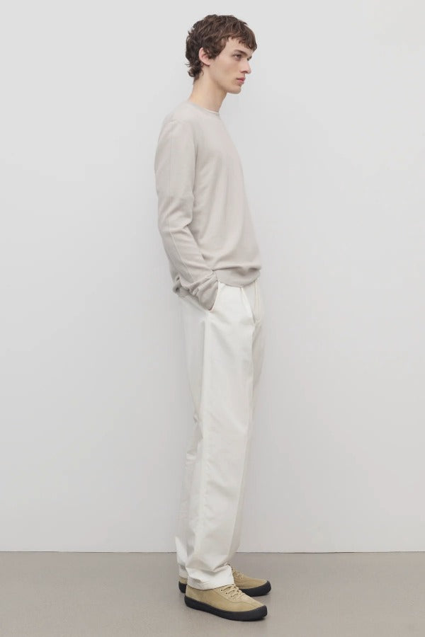 Side view of white belamy pant on model wearing beige top and sneakers, against a white background.