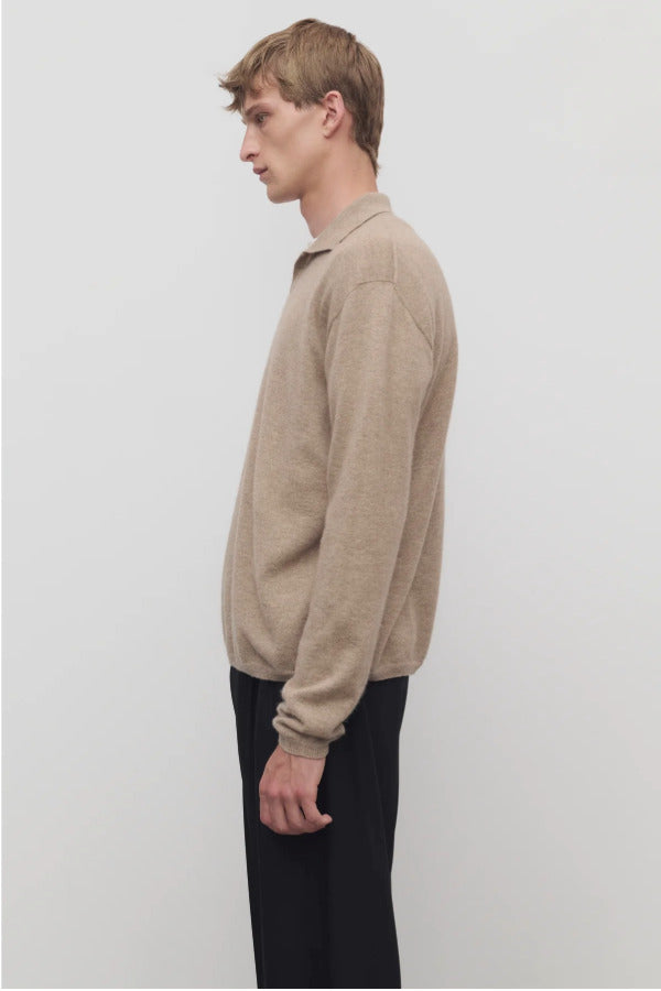 Side view of taupe men's franz sweater on model wearing black trousers, against a white background