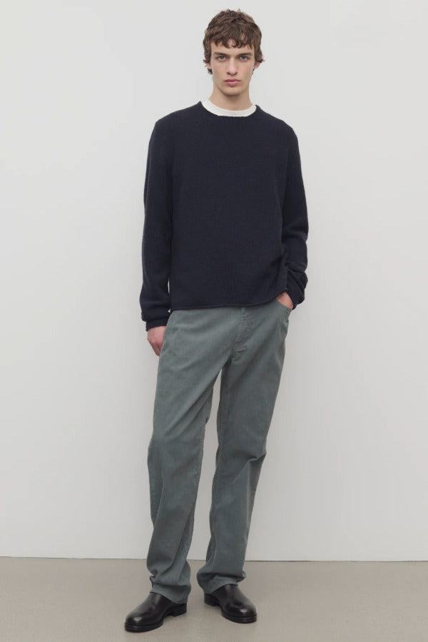 Front view of grey mens fred pant on model wearing black sweater and boots, against a white background.