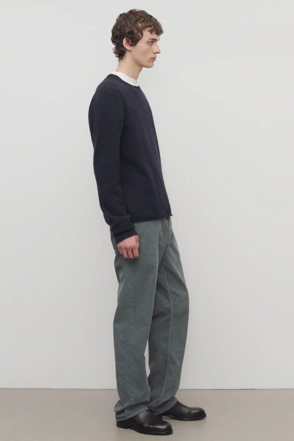Side view of grey men's fred pants on model wearing black sweater and boots, against a white background.
